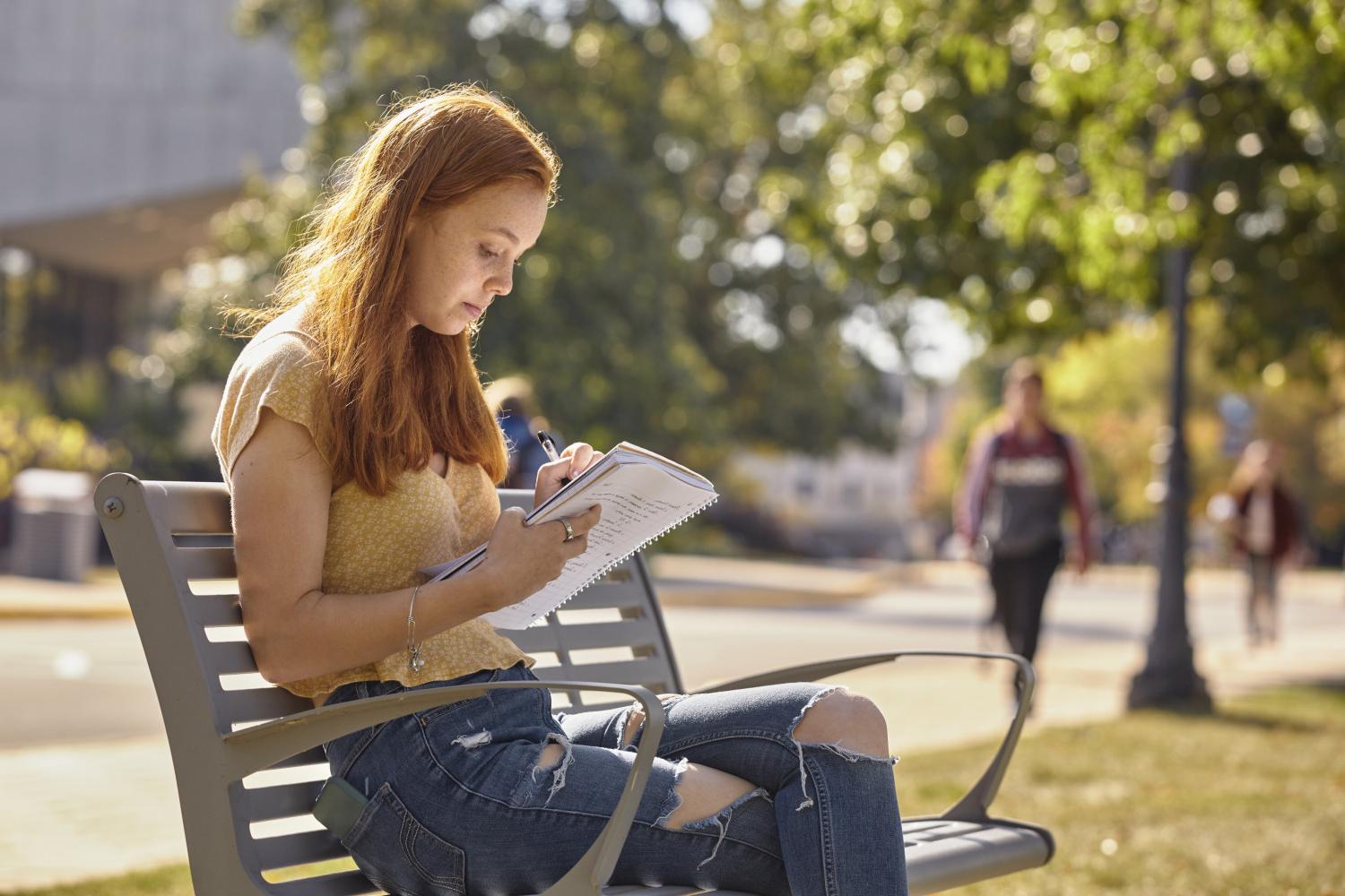 一位<a href='http://r0.m3csl.net'>全球十大赌钱排行app</a>学院的学生在校园里的长椅上读书.